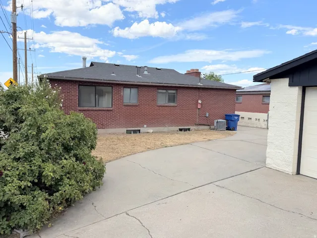 Brick exterior with a dark shingle roof, accompanied by a concrete driveway