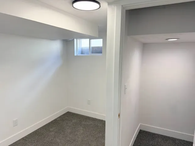 Recessed window, plush gray carpeting, white walls, and contemporary ceiling lighting
