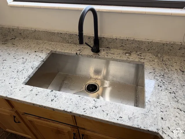 Granite-style countertop with an undermount stainless steel sink and a matte black gooseneck faucet
