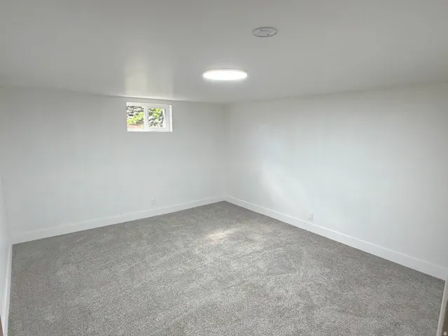 Recessed lighting fixture, light gray carpeting, white painted walls, white trim, and a single window