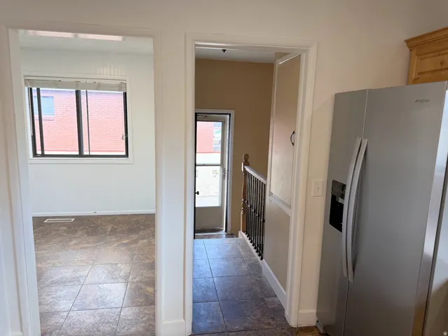 Tile flooring throughout, white baseboards, and a paneled wall in the room