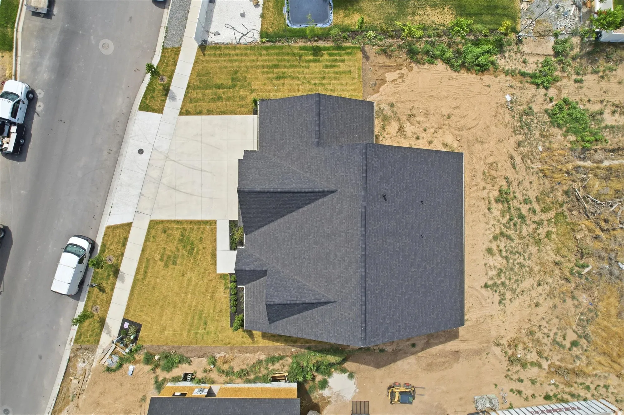 New construction residence with dark shingle roofing, concrete driveway, and a partially landscaped front yard