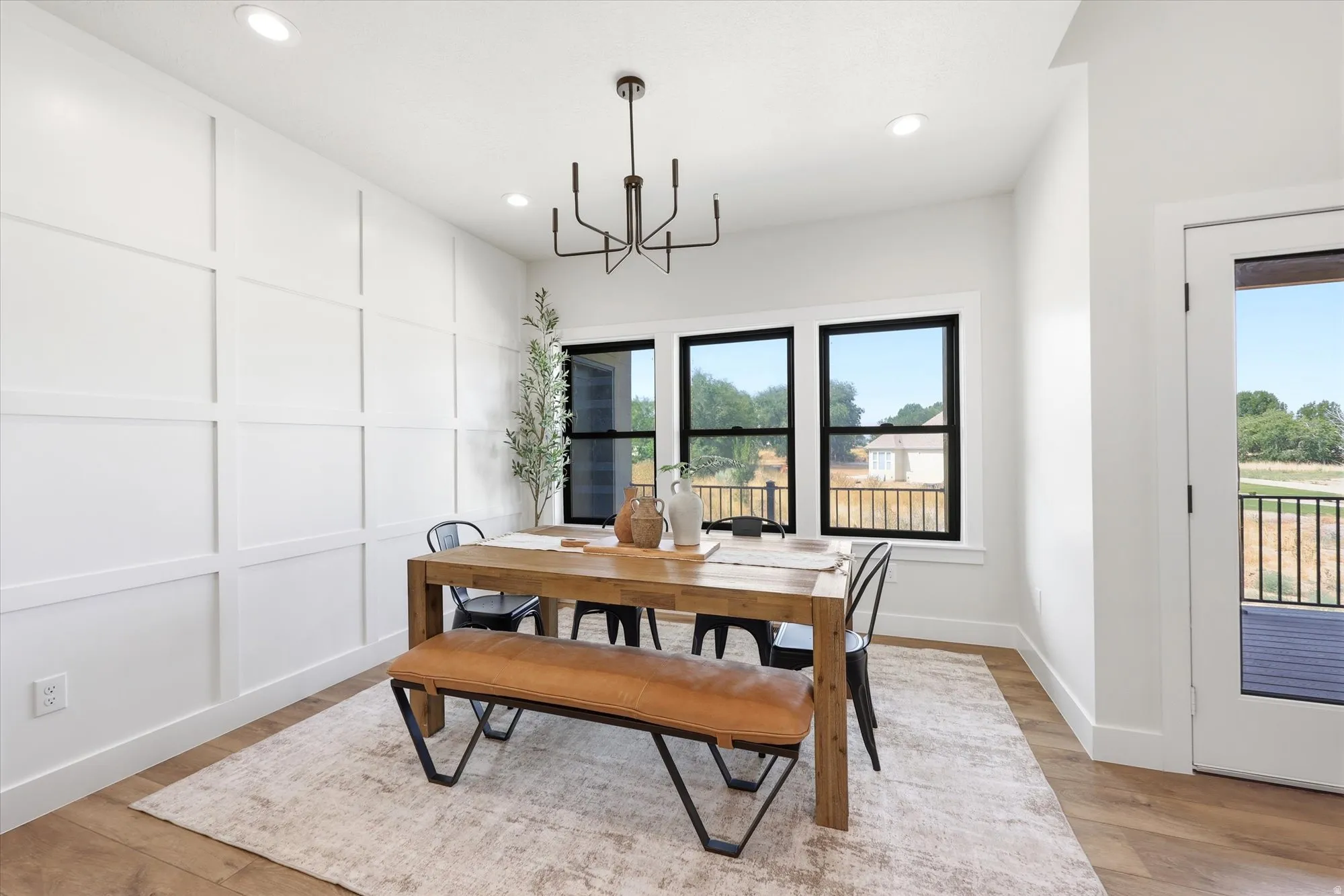 Board and batten accent wall, recessed ceiling lighting, wood-finish flooring, black window frames, and contemporary chandelier