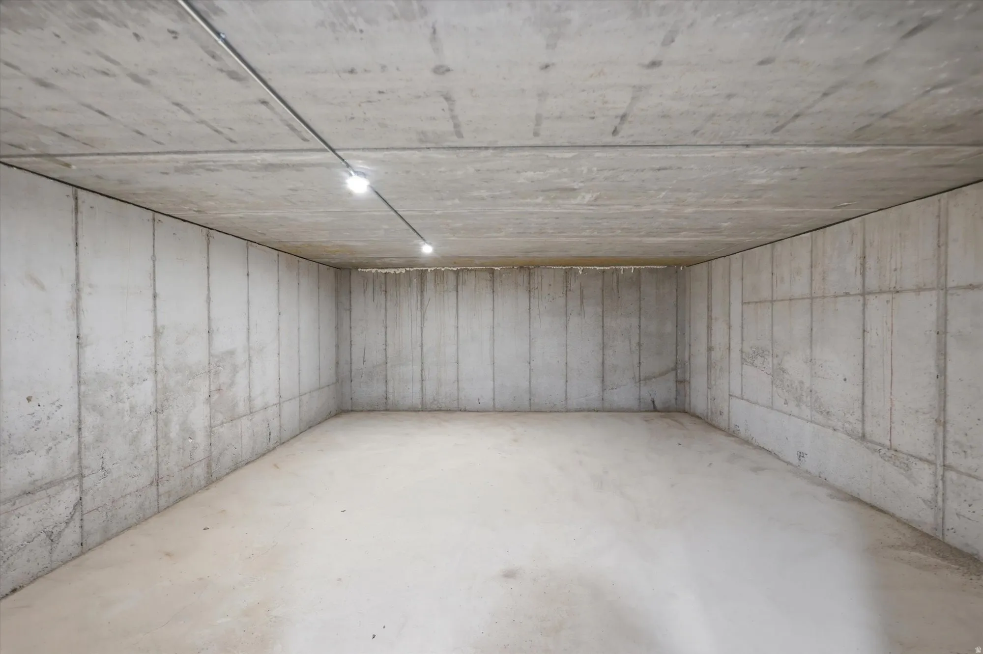 Suspended concrete slab underneath garage, concrete flooring, and ceiling-mounted track lighting