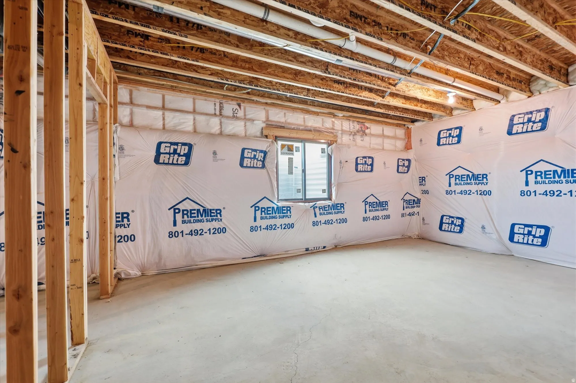 Unfinished basement with exposed ceiling joists, wood framing, concrete flooring, and a single window opening