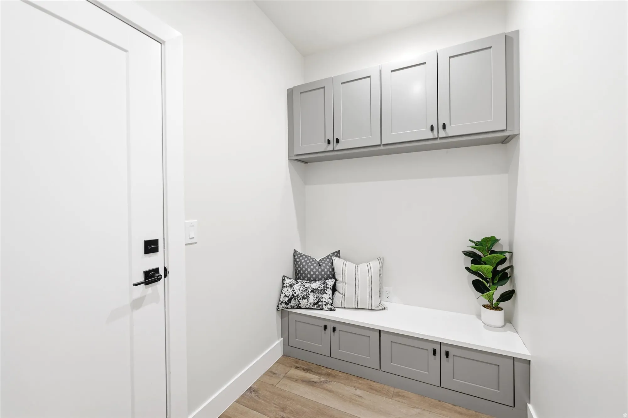 Built-in cabinetry with shaker-style doors, built-in bench seating, wood-finish flooring, and a flat-panel door with matte black hardware