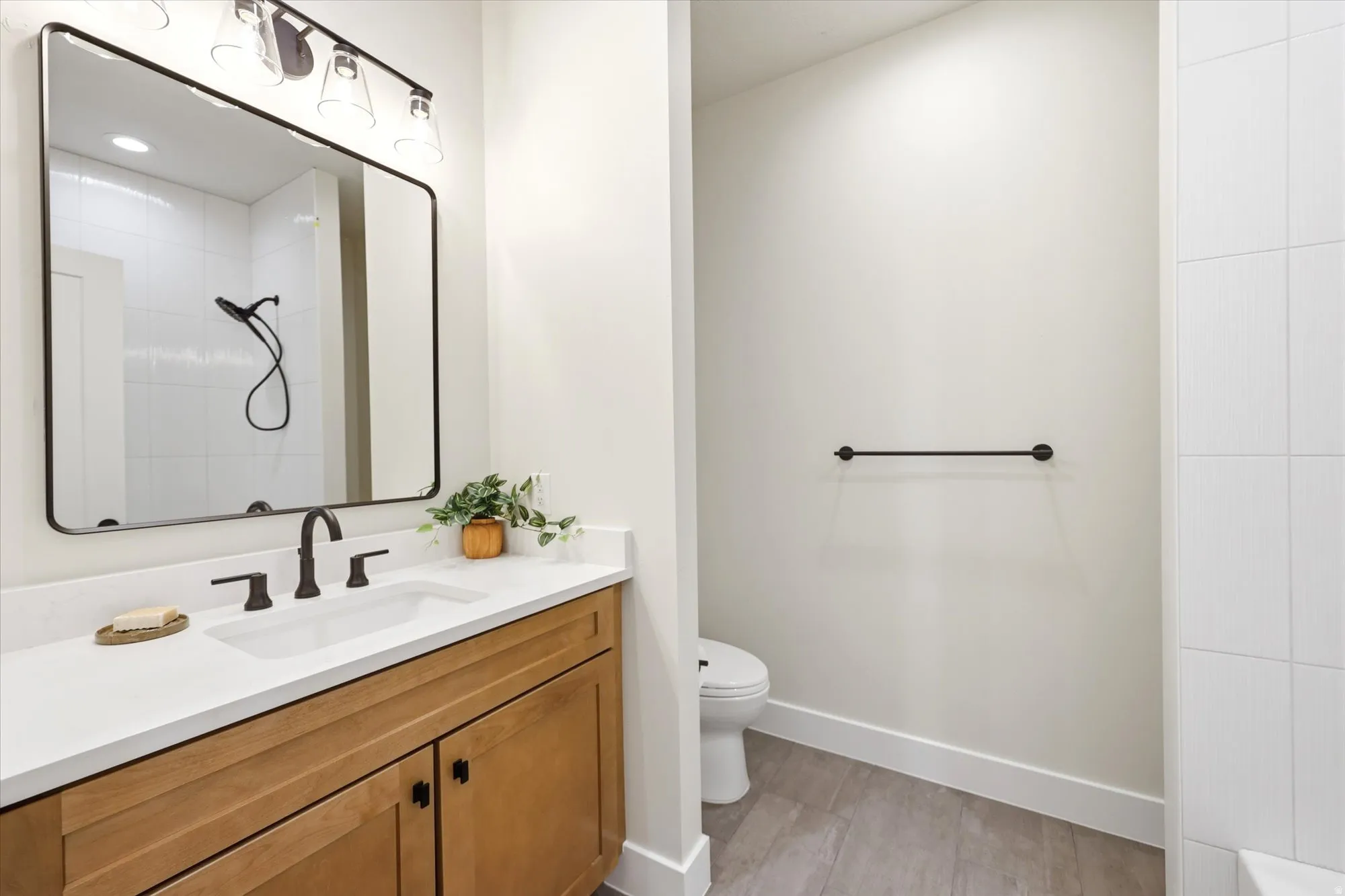 Vanity with wood-finish cabinetry, white countertop, and integrated sink