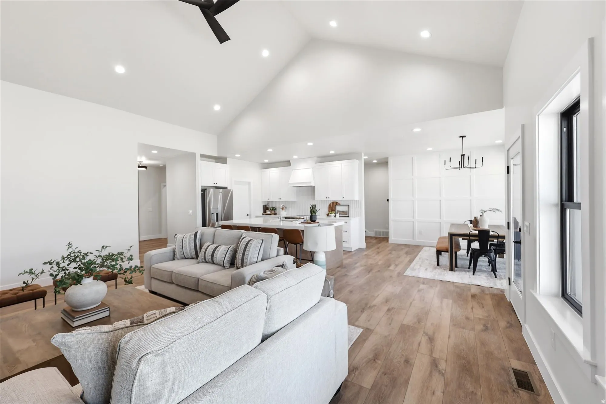 Vaulted ceilings, wood-finish flooring, recessed lighting, white shaker cabinetry, and a kitchen island with seating
