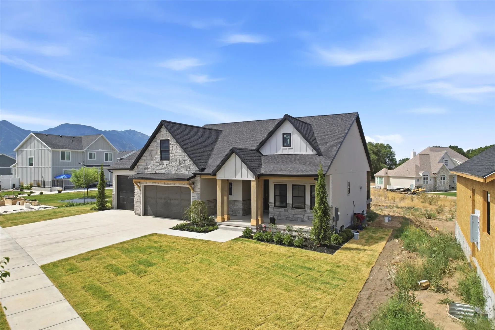 Contemporary exterior with stone facade, dark-framed windows, a two-car garage, and a concrete driveway