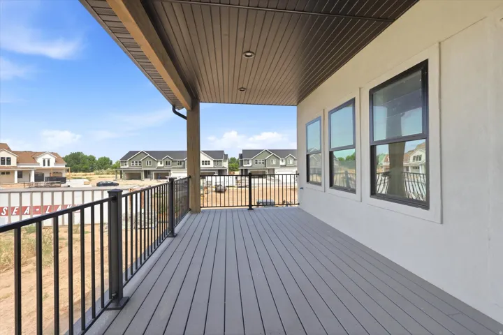 Expansive outdoor deck featuring composite decking, black metal railings, and a solid overhead covering with recessed lighting