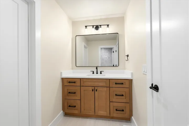 Wood-finish vanity with white countertop, undermount sink, and matte black hardware