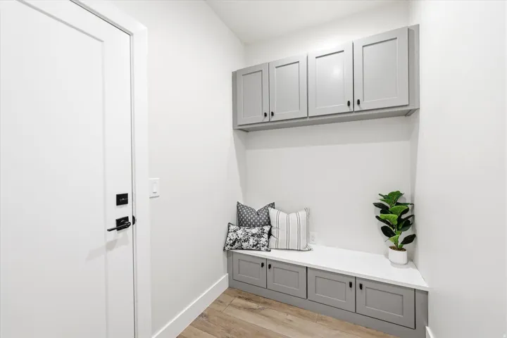 Built-in cabinetry with shaker-style doors, built-in bench seating, wood-finish flooring, and a flat-panel door with matte black hardware