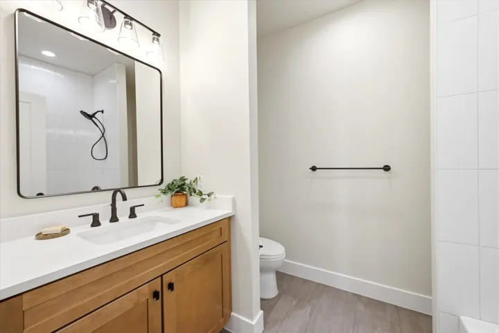 Vanity with wood-finish cabinetry, white countertop, and integrated sink
