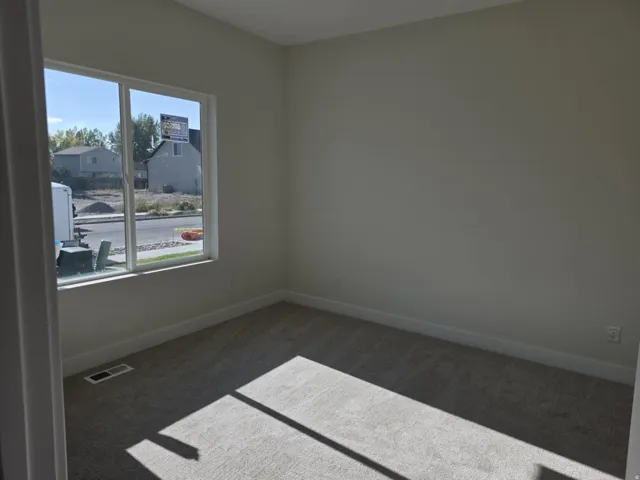 Neutral-toned carpeting with light-colored walls and a bright window