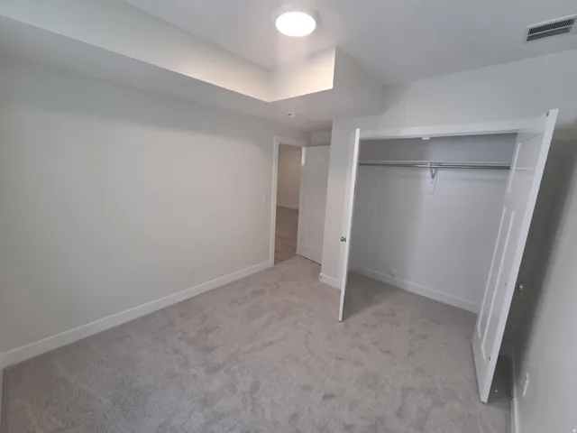 Recessed ceiling detail, flush mount lighting, light gray wall finish, gray carpet flooring, and bi-fold closet doors