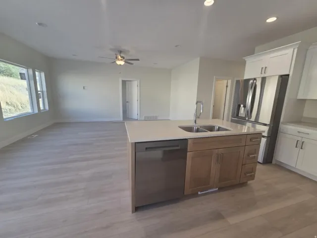 Open-concept living area with wood-finish flooring, a contemporary ceiling fan, and recessed lighting