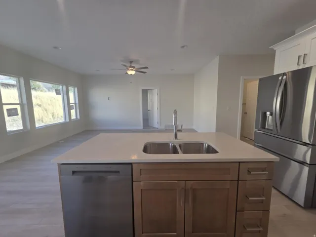 Kitchen island with an undermount double-basin sink, stainless steel dishwasher, and quartz countertop