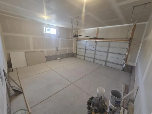 Spacious garage with exposed drywall, a single window, and a sectioned overhead door