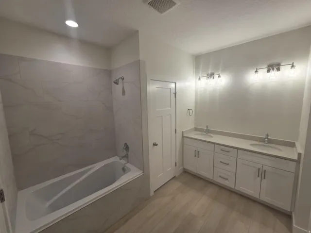 Dual vanity with integrated sinks, white cabinetry, chrome fixtures, and stone countertops