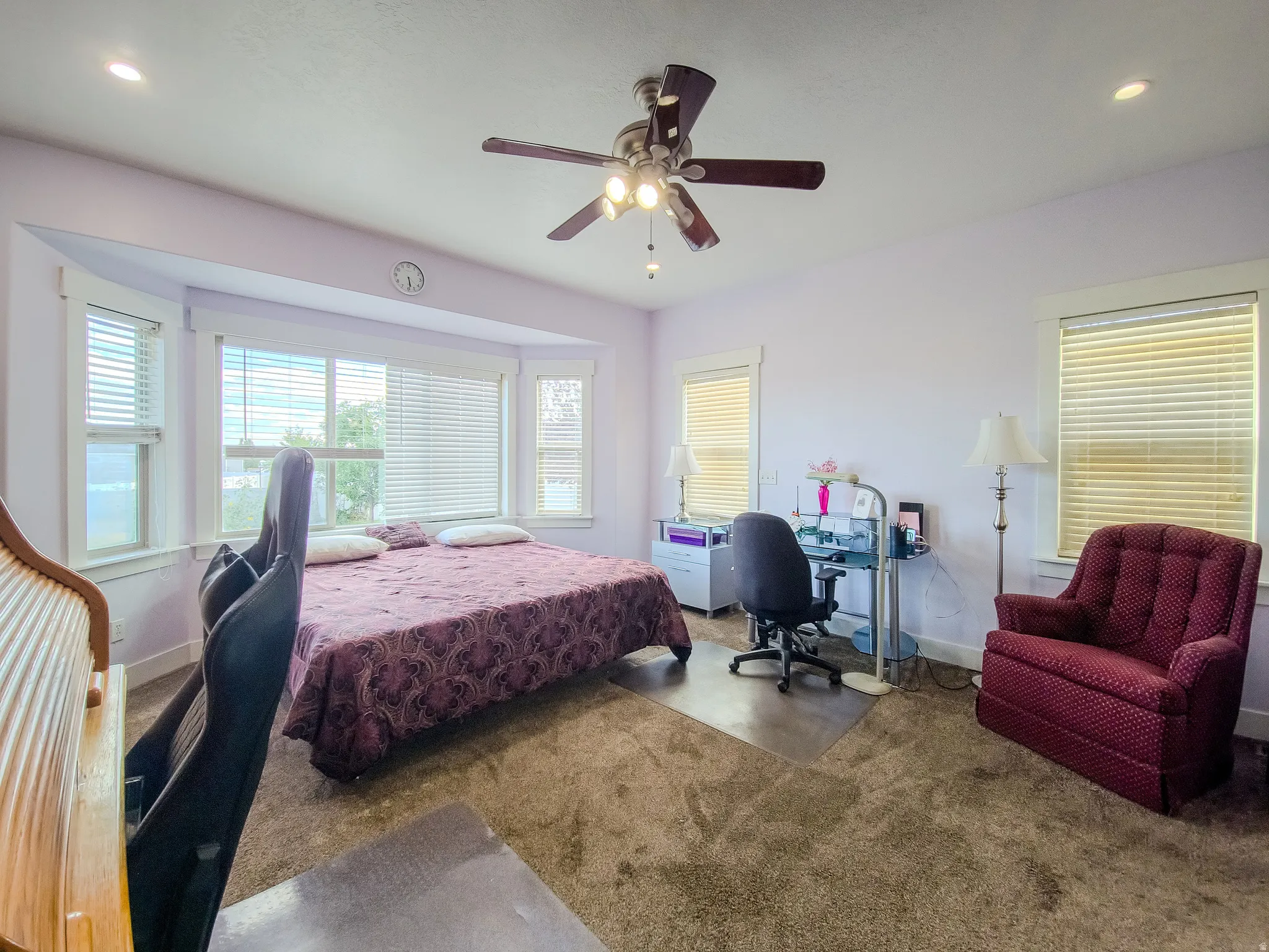 Recessed lighting, ceiling fan with light fixture, bay window with blinds, carpet flooring, and white trim