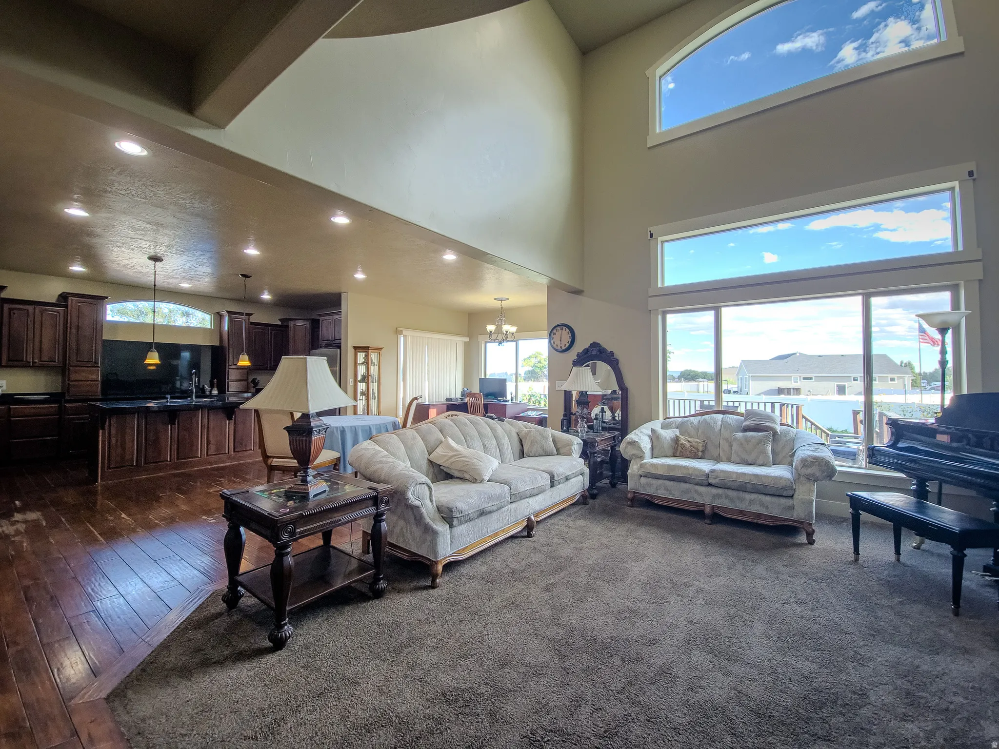 Vaulted ceiling, large windows, wood-finish flooring, recessed lighting, and rich wood cabinetry