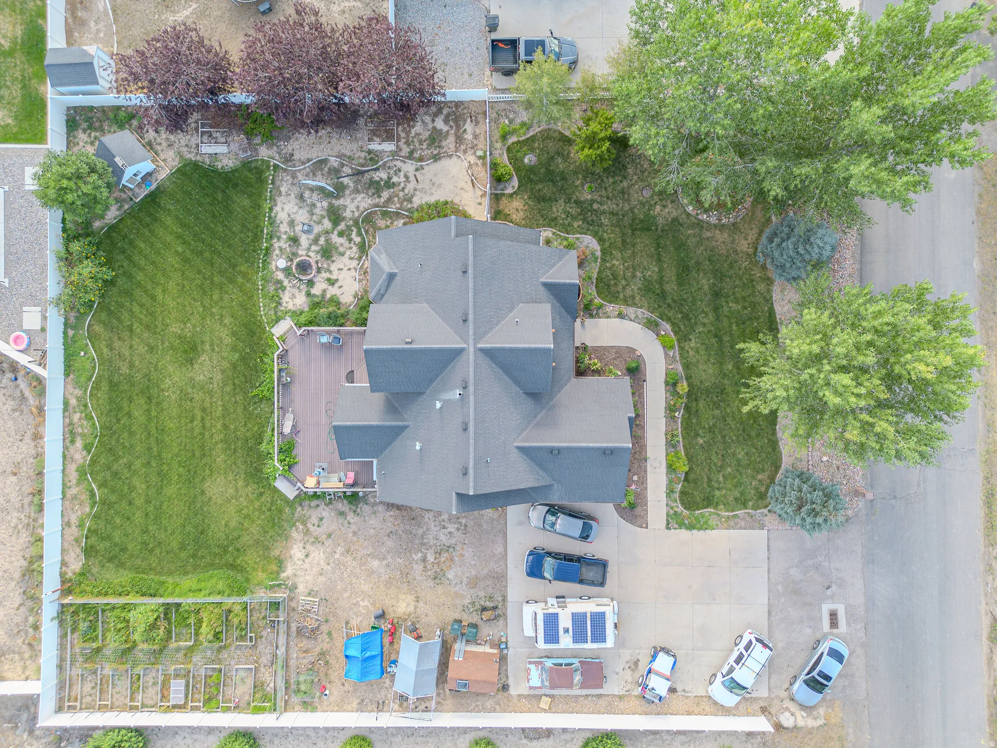 Expansive property featuring a multi-gabled roofline, concrete driveway, and a wooden deck