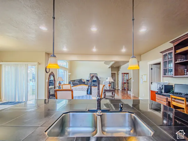 Stainless steel dual-basin sink with a dark-toned faucet, dark countertops, and pendant lighting