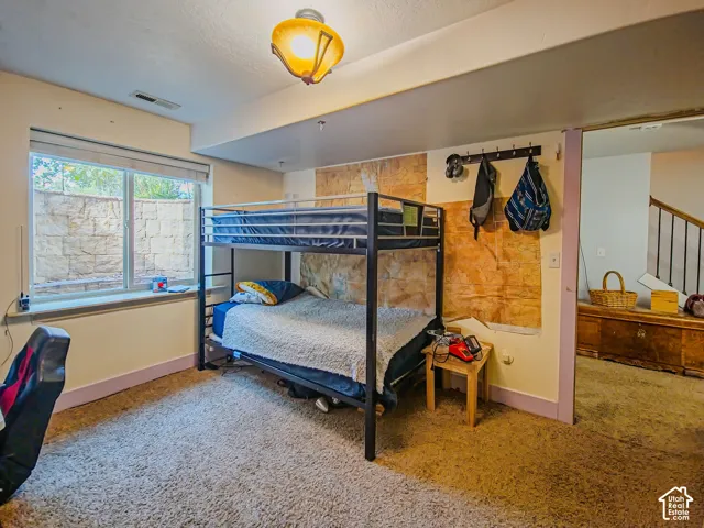 Carpeted room with a large window, a partial textured wall, and overhead lighting