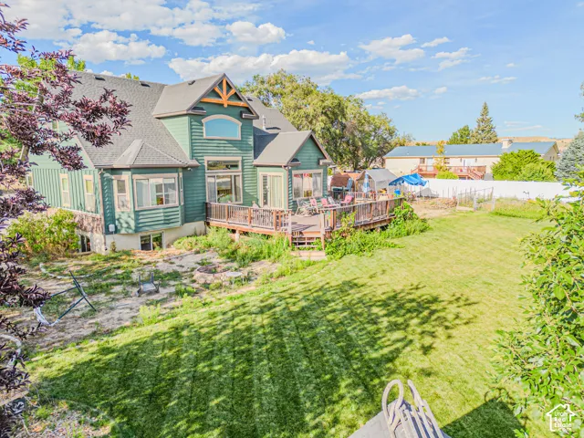 Expansive backyard featuring a manicured lawn, multi-level wood deck, and established trees