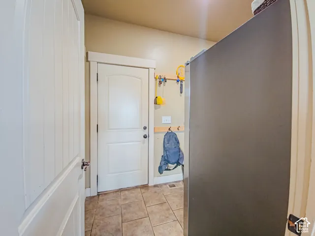 Recessed lighting illuminates the space, which features tiled flooring, a paneled door with a simple trim, and a second paneled door
