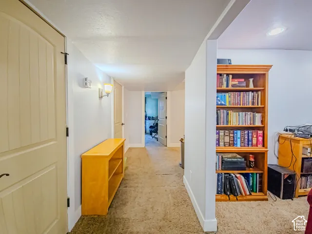 Wall-mounted sconce lighting, warm wood-finish built-in shelving, carpet flooring