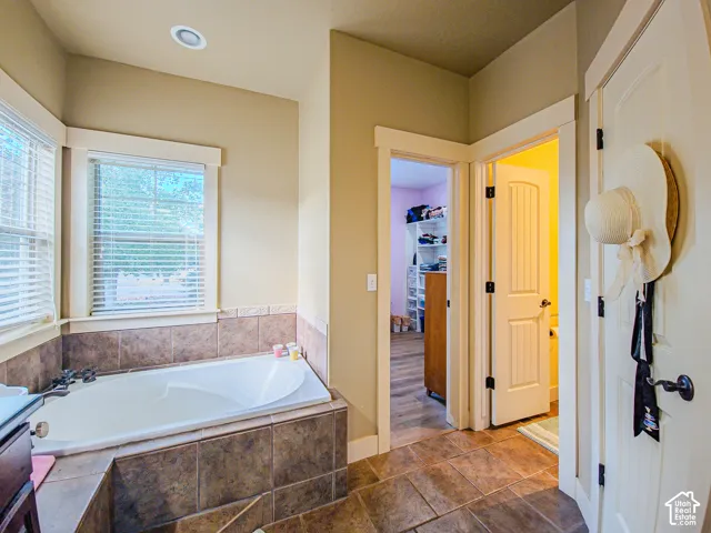 Built-in soaking tub with tile surround, paired with a large window and recessed lighting