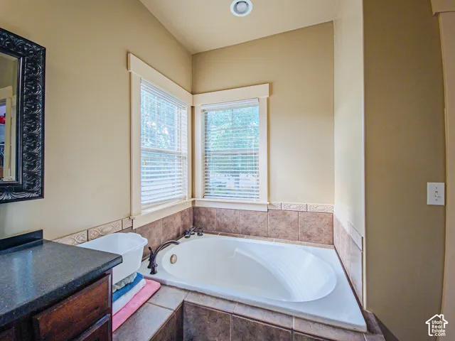 Built-in soaking tub with corner windows, tile surround, and recessed lighting
