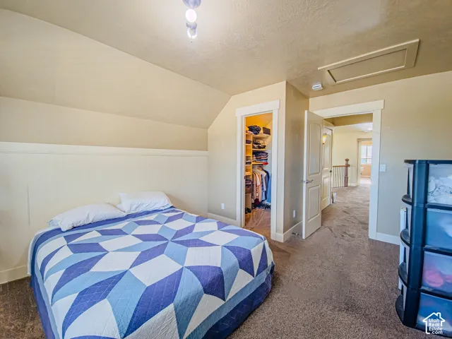 Attic bedroom featuring angled ceilings, carpeted flooring, and a built-in closet system