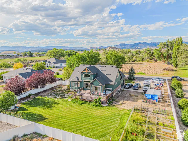 Two-story residential structure with a gable roof, an expansive rear deck, and a fenced backyard with a manicured lawn