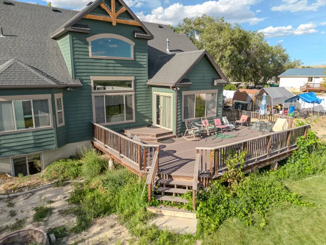 Expansive multi-level deck with wood railing, leading to a sliding glass door entry