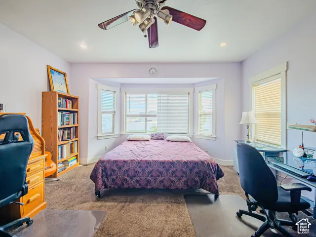 Recessed lighting, ceiling fan, bay window with blinds, and neutral carpet flooring