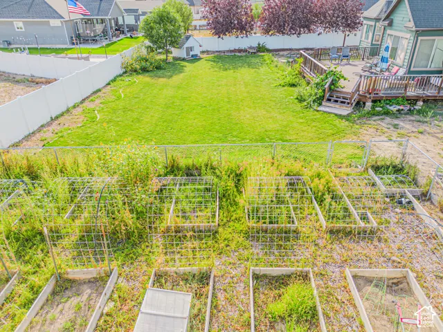 Expansive backyard featuring a lush lawn, raised garden beds, and a multi-level wood deck