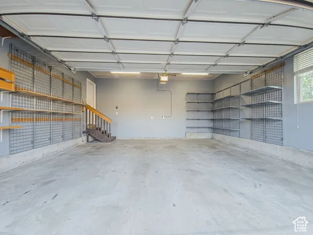 Spacious garage with extensive built-in shelving, concrete flooring, and a window for natural light