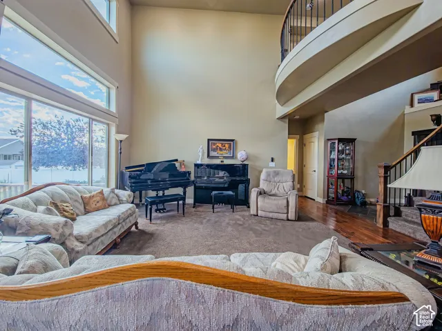 Two-story windows, vaulted ceiling, curved balcony with iron railing, wood-finish flooring, and carpeted area