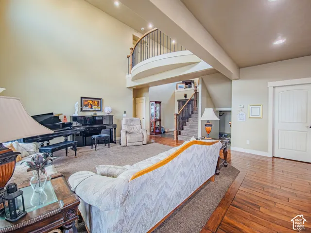Two-story ceiling, upper-level balcony with metal railing, wood-finish flooring, staircase with wood newel posts, and paneled interior door