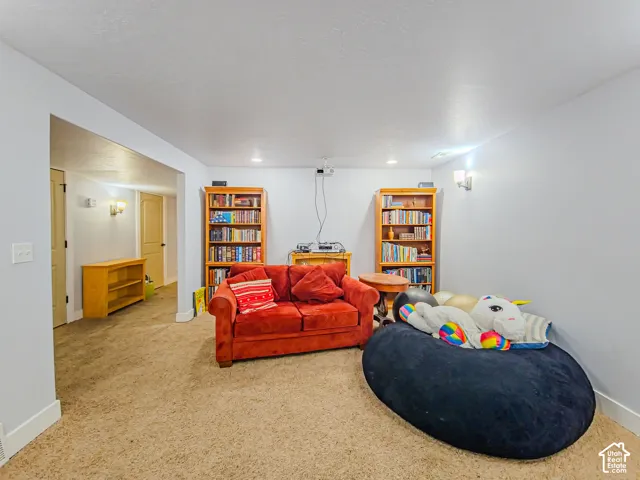 Recessed lighting, wall sconces, and light-toned walls illuminate the carpeted area