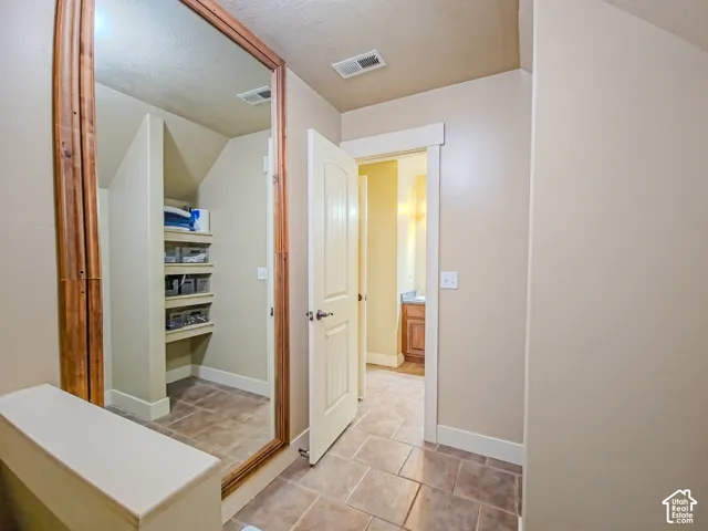 Full-length mirror with wood-finish framing, built-in shelving, and tile flooring