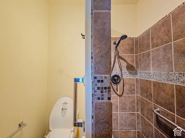 Tiled shower enclosure with a mosaic accent band, equipped with a handheld shower fixture