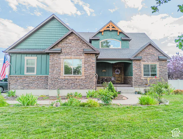 Stone and shingle exterior with a covered front porch and an arched window dormer