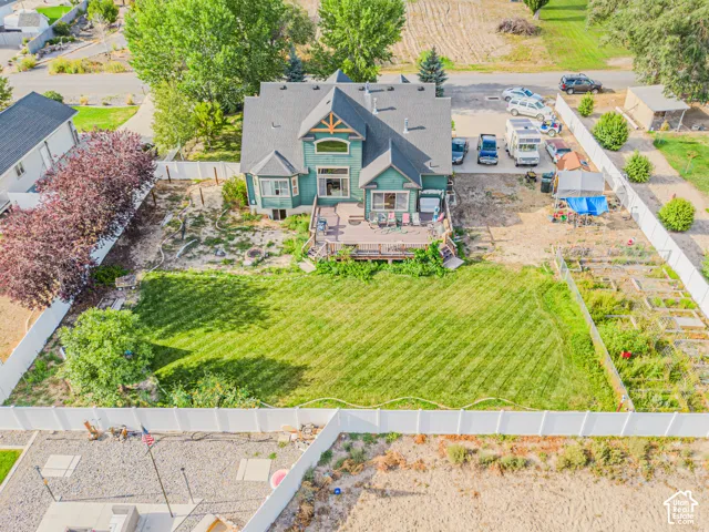 Two-story property with a multi-level deck, fenced backyard with manicured lawn, and a gravel driveway