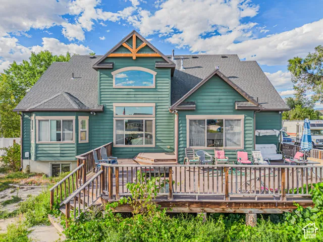 Rear elevation with teal siding, multiple windows, an upper arched window, a gabled accent, and a wood deck