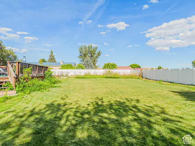 Expansive grass lawn with a wood deck and white panel fencing