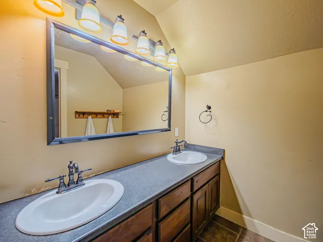 Dual undermount sinks with brushed nickel faucets, dark wood cabinetry, a large framed mirror, and a multi-bulb vanity light fixture