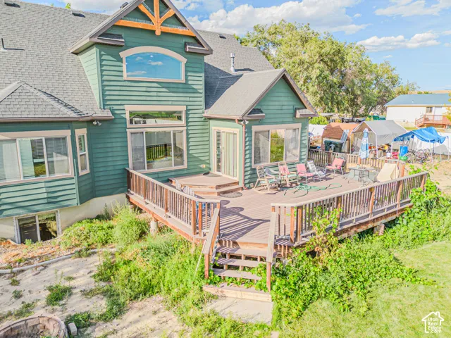 Expansive multi-level wood deck, green siding, and a prominent arched window on the upper level